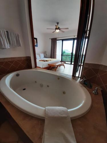 a large white tub in a bathroom with a living room at Villas Mayaluum Cozumel in Cozumel