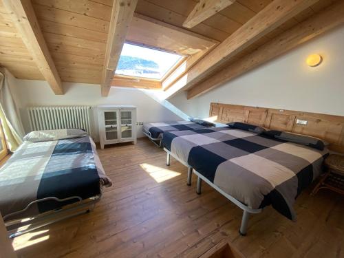two beds in a room with a large window at Chalet dei Reparti Bormio in Bormio
