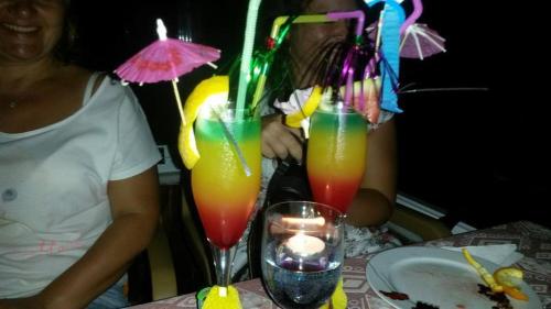 a woman sitting at a table with two drinks at Hotel Grün in Kızılot