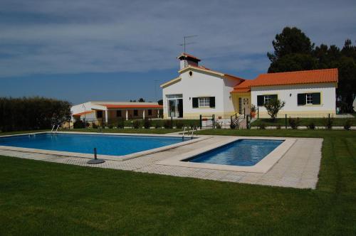 a house with a swimming pool in front of a house at Quinta da Fonte de Grandola in Grândola