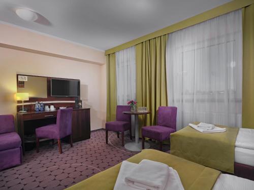 a hotel room with two beds and purple chairs at Aparthotel Lumen in Kraków