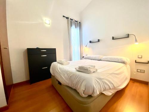 een slaapkamer met een bed met witte lakens en een zwarte dressoir bij Orquídea 7.3 in El Tarter