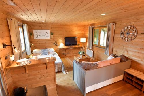 un salon avec des boiseries et une télévision dans l'établissement Le Chalet d’Eliot, à Chevigny