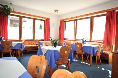ein Esszimmer mit blauen Tischen, Stühlen und Fenstern in der Unterkunft Pension Fundus in Pfunds
