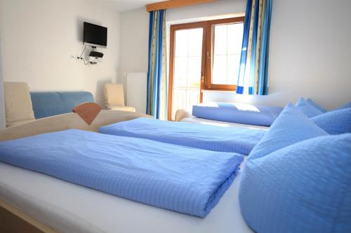 een kamer met drie bedden met blauwe lakens bij Pension Fundus in Pfunds