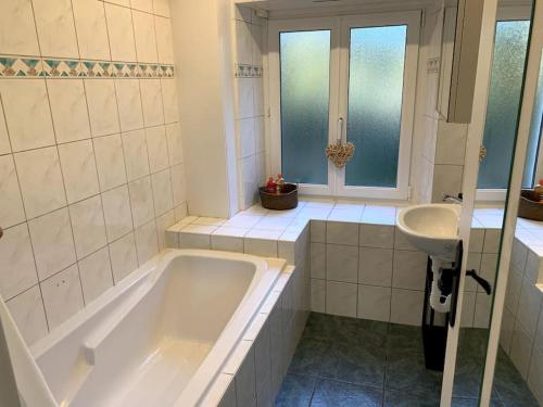 La salle de bains blanche est pourvue d'une baignoire et d'un lavabo. dans l'établissement L'Atelier - T1 près de la gare de Mulhouse, à Mulhouse