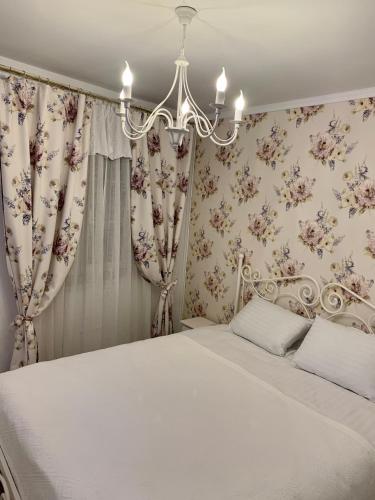 a bedroom with a white bed with curtains and a chandelier at The Hedgehog Boutique House & Garden in Cluj-Napoca