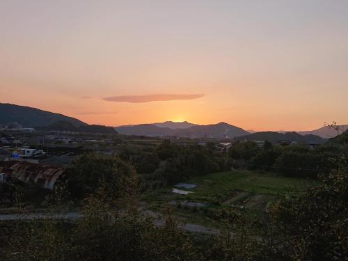 un coucher de soleil sur une ville avec des montagnes en arrière-plan dans l'établissement ＬＯＤＧＥ ｎ"ｔｒｉｂｅ - Vacation STAY 79116v, à Nichinan