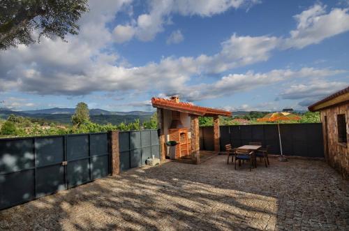 une terrasse avec une table et une petite maison dans l'établissement Casa das Vinhas Camélias de BastoTurismo Rural, à Castelbuono