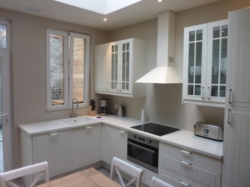 a kitchen with white cabinets and a sink at Aimée in Ypres