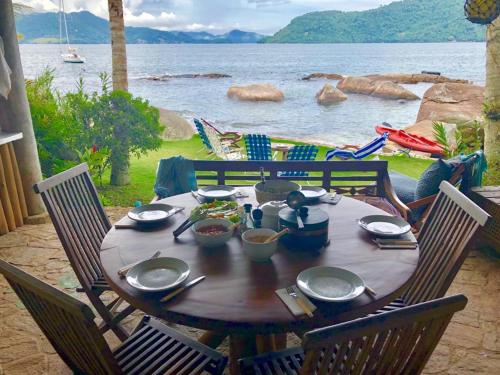 a wooden table with food on it with a view of the water at Angra House - Linda Casa em ILHA in Angra dos Reis