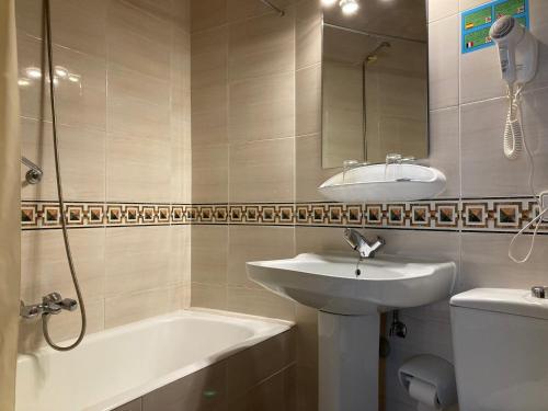 a bathroom with a sink and a mirror and a tub at Hotel Condal in Salamanca