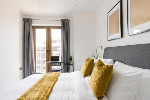 - une chambre avec un grand lit blanc et des oreillers jaunes dans l'établissement Apartment- St Albans with WiFi & Close to Station, à St Albans