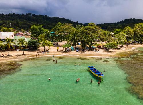 people in the water at a beach with a boat at Namuwoki Lodge in Puerto Viejo