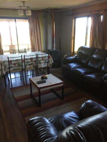 a living room with a leather couch and a table at CASAS Y CABAÑAS CUMBRES DEL SOL in Castro