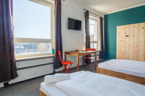 a bedroom with two beds and a desk and a window at Private Rooms Karlsruhe near station in Karlsruhe