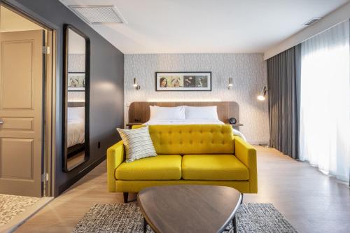 a bedroom with a yellow couch and a bed at Hôtel Versō in Magog-Orford