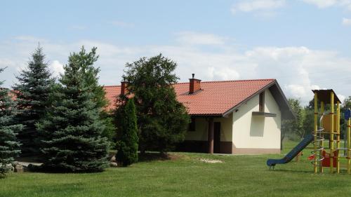 a house with a playground in the yard at Tawerna-Stawiska in Garbatka-Letnisko