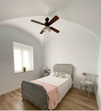 Casa Rural La abuela في El Campo: غرفة نوم مع مروحة سقف وسرير