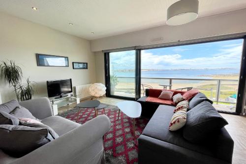 un salon avec un canapé et une vue sur l'océan dans l'établissement Luxury T3 standing 2 - Vue mer exceptionnelle 180, à Larmor-Plage