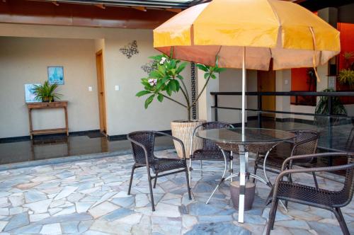 a table and chairs with an umbrella in a lobby at Hotel Pousada Parque das Águas in Olímpia