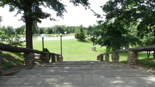 a wooden bridge in a park with trees and a field at Tawerna-Stawiska in Garbatka-Letnisko
