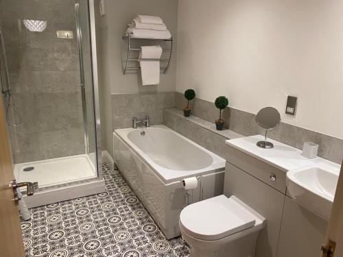 a bathroom with a tub and a toilet and a shower at GS - Luxury, modern town centre, 2 beds, free parking for one vehicle in Stratford-upon-Avon