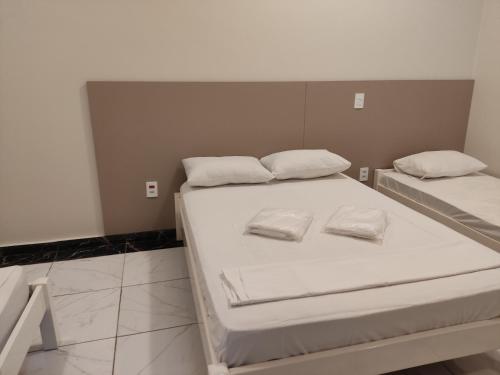 Duas camas com almofadas brancas num quarto em Liv Hotel em Porto Ferreira
