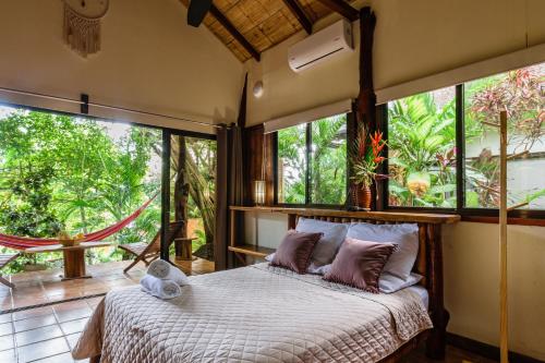 1 dormitorio con 1 cama en una habitación con ventanas en Funky Monkey Lodge en Santa Teresa Beach