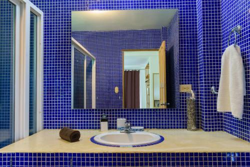 a blue tiled bathroom with a sink and a mirror at Funky Monkey Lodge in Santa Teresa Beach
