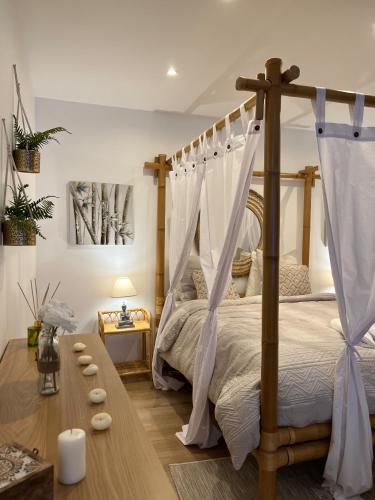- une chambre avec un lit à baldaquin et une table en bois dans l'établissement PARENTHESE LOVE - Bali Mon Amour Suite Balneo SPA Proche Orly-Paris, à La Ville-du-Bois