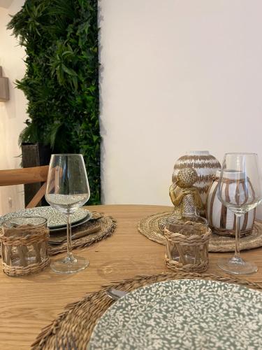 une table en bois avec deux verres à vin dessus dans l'établissement PARENTHESE LOVE - Bali Mon Amour Suite Balneo SPA Proche Orly-Paris, à La Ville-du-Bois