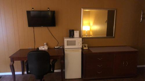 a hotel room with a desk and a refrigerator and a television at Moose Motel in Smooth Rock Falls