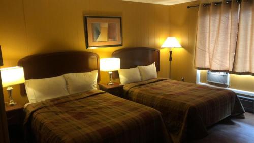 twee bedden in een hotelkamer met twee lampen bij Moose Motel in Smooth Rock Falls
