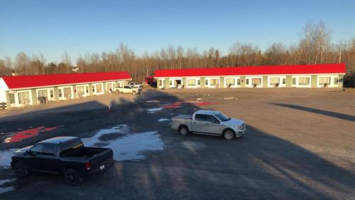 twee auto's geparkeerd op een parkeerplaats voor een gebouw bij Moose Motel in Smooth Rock Falls