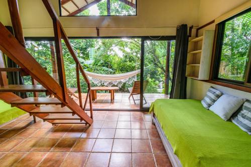 a room with a bed and a hammock in it at Funky Monkey Lodge in Santa Teresa Beach