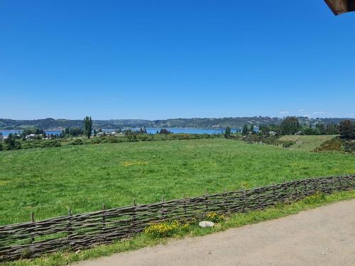 a field of green grass with a wooden fence at CASAS Y CABAÑAS CUMBRES DEL SOL in Castro