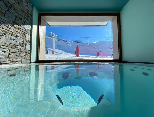 a swimming pool with a window in a building at Alberta Hotel & Spa in Val Thorens