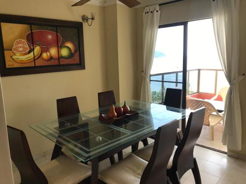 a dining room with a glass table and chairs at Apartamento Los Laureles Rodadero in Santa Marta