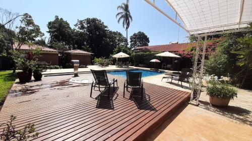 a wooden deck with chairs and a swimming pool at Fazenda Santa Clementina in Araras