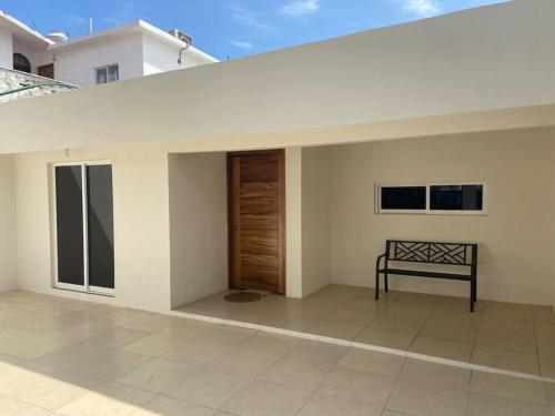 a white house with a wooden door and a bench at Casa de verano totalmente equipada y amueblada in Santa Cruz Huatulco