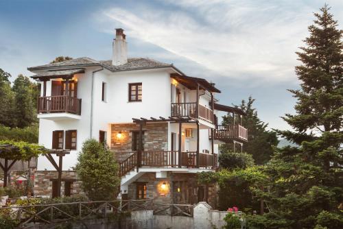 a large white house with balconies and trees at Tampakeika in Mouresi