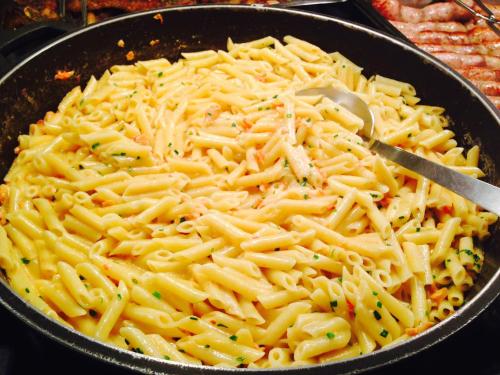 a pan filled with macaroni and cheese with a spoon at Hostal ROM Familiar in Roses
