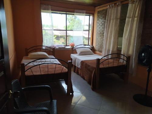 two beds in a room with a window at Villas de León in Leticia