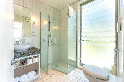 a bathroom with a shower and a toilet and a sink at The Sands - Apartment 26 - Stay Waiheke in Onetangi