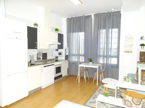 a kitchen and dining room with white cabinets and a table at ESTUDIO IDEAL PARA VACACIONES Y TRABAJO in Vigo