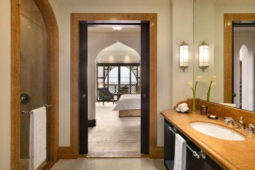 a bathroom with a sink and a room with a bed at Shangri-La Qaryat Al Beri, Abu Dhabi in Abu Dhabi