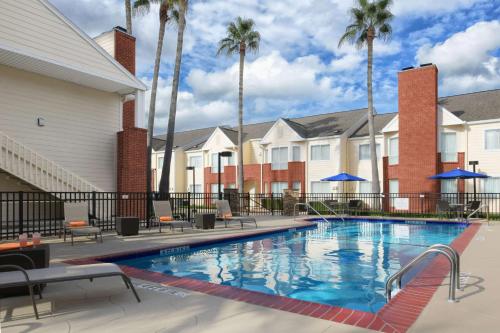 a swimming pool at a resort with palm trees at Sonesta ES Suites Houston - NASA Clear Lake in Webster