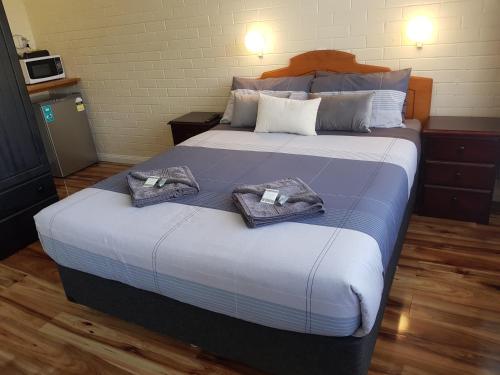 1 dormitorio con 1 cama grande y toallas. en Whyalla Country Inn Motel, en Whyalla