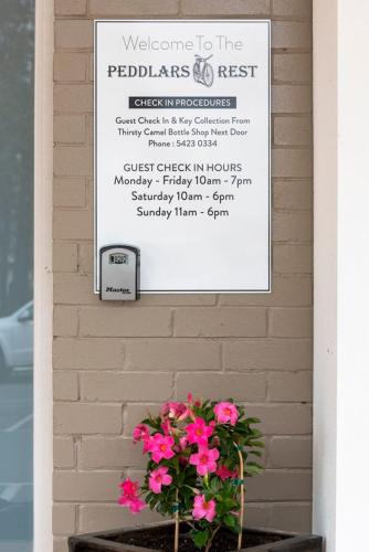 a sign on a wall with a bunch of pink flowers at Peddlars Rest in Toogoolawah